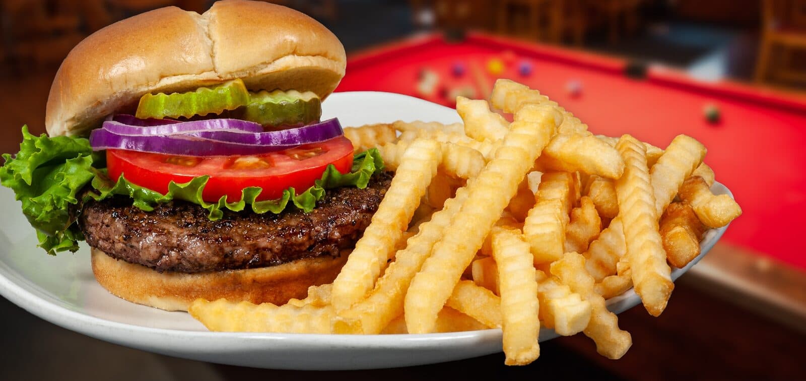 Signature cheeseburger and crinkle fries on a pool table
